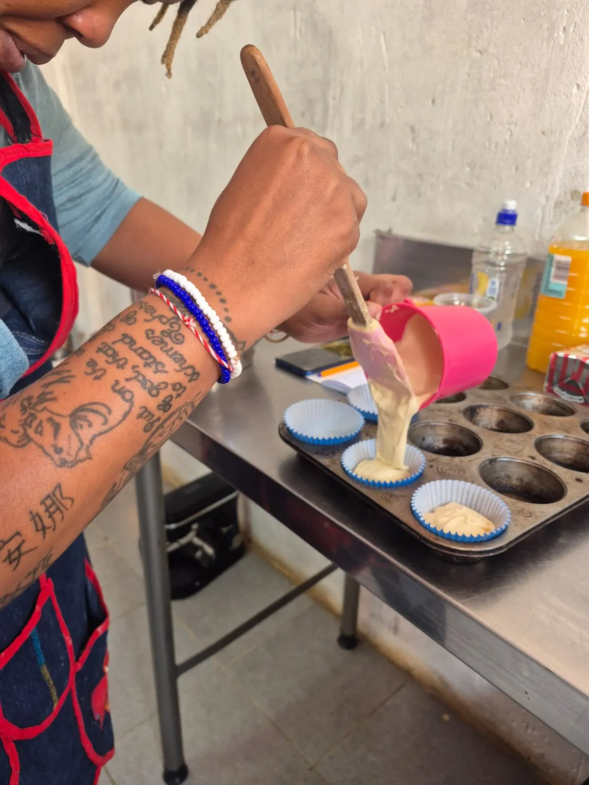 A Rosy's Cakes and Events trainee pouring cupcake batter into a baking tin
