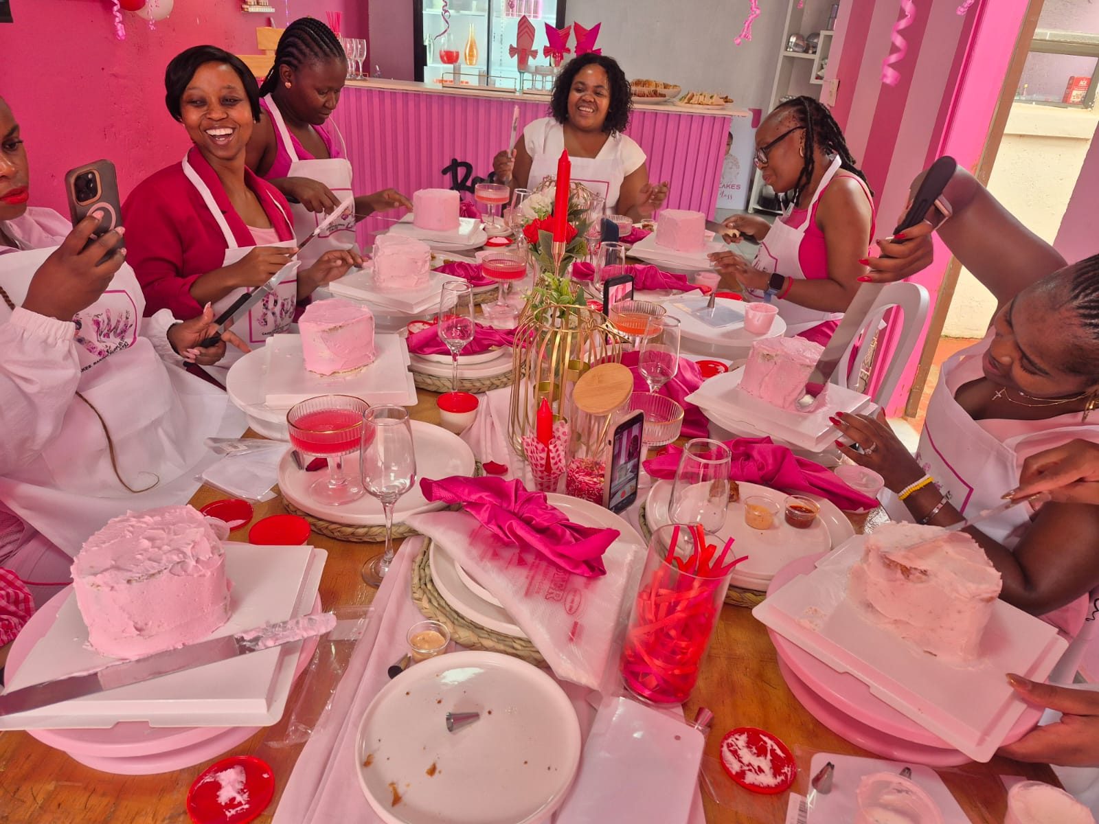 A group of students decorating their own pink cakes together at a Rosy's Cakes and Events class